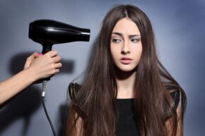 long haired girl looks scared by blow drier