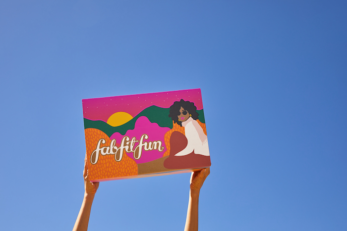 Girl holding Fall FabFitFun box up in air