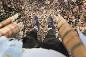 downward angle of girl standing looking down at fall leaves on ground