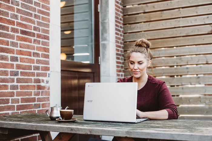 Girl with coffee cup next to her on laptop