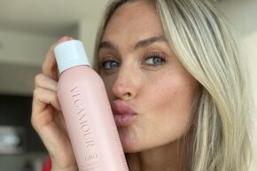 blonde girl holding vegamour gro dry shampoo against face