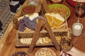 macy blackwell wooden tiered app tray on wooden table with food and drink on it and around