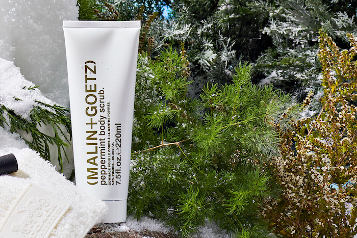 Malin + Goetz Peppermint Body Scrub in wintery background with green trees behind