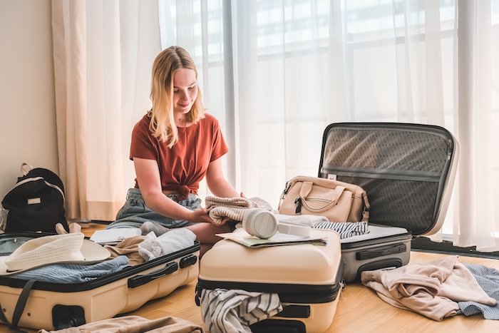 Girl sitting on floor with open suitcases around her packing