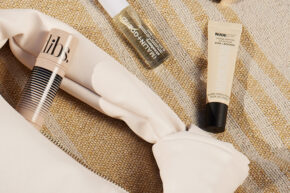 beauty products spilling out of bag on striped towel
